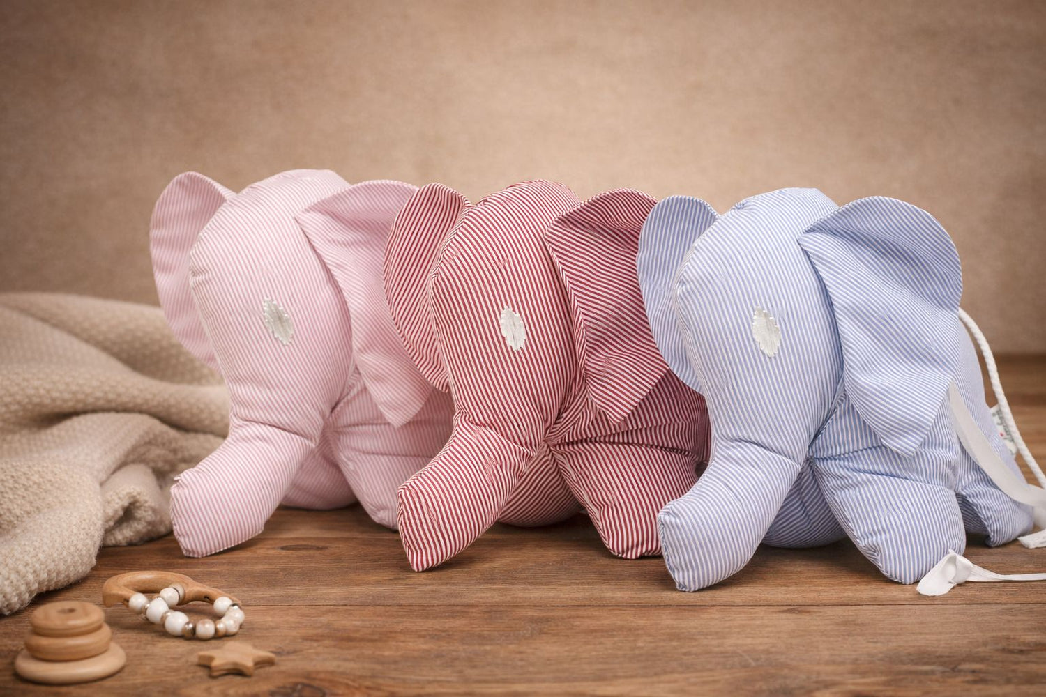 Tavolinchen Stoffelefanten mit feinem Streifenmuster in Rosa, Rot und Blau auf Holzboden