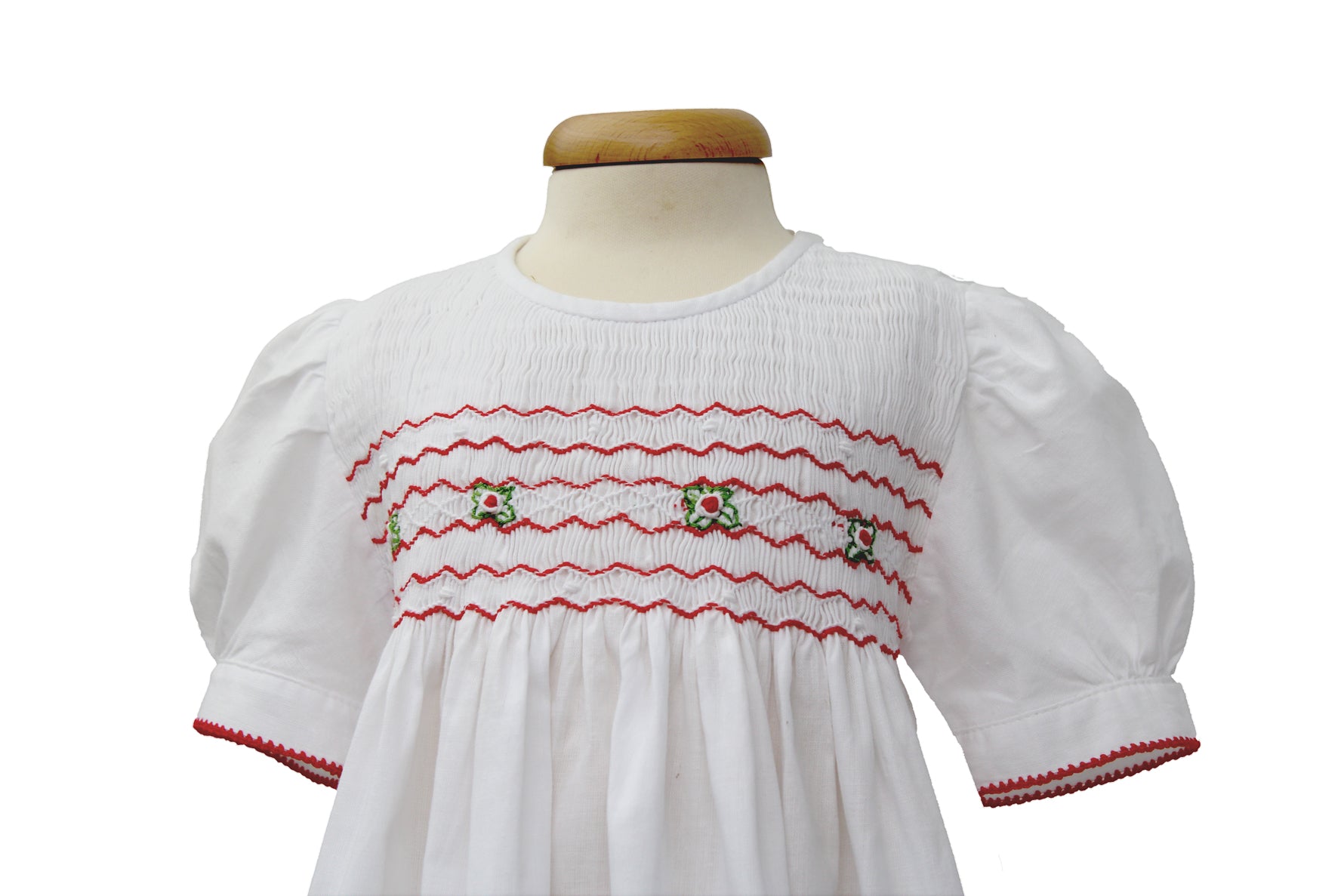 Detailaufnahme Tavolinchen Mädchenkleid weiß mit Smokstickerei, roten Zickzack-Borten und gestickten Blümchen