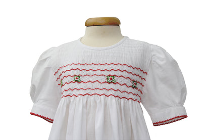 Detailaufnahme Tavolinchen Mädchenkleid weiß mit Smokstickerei, roten Zickzack-Borten und gestickten Blümchen